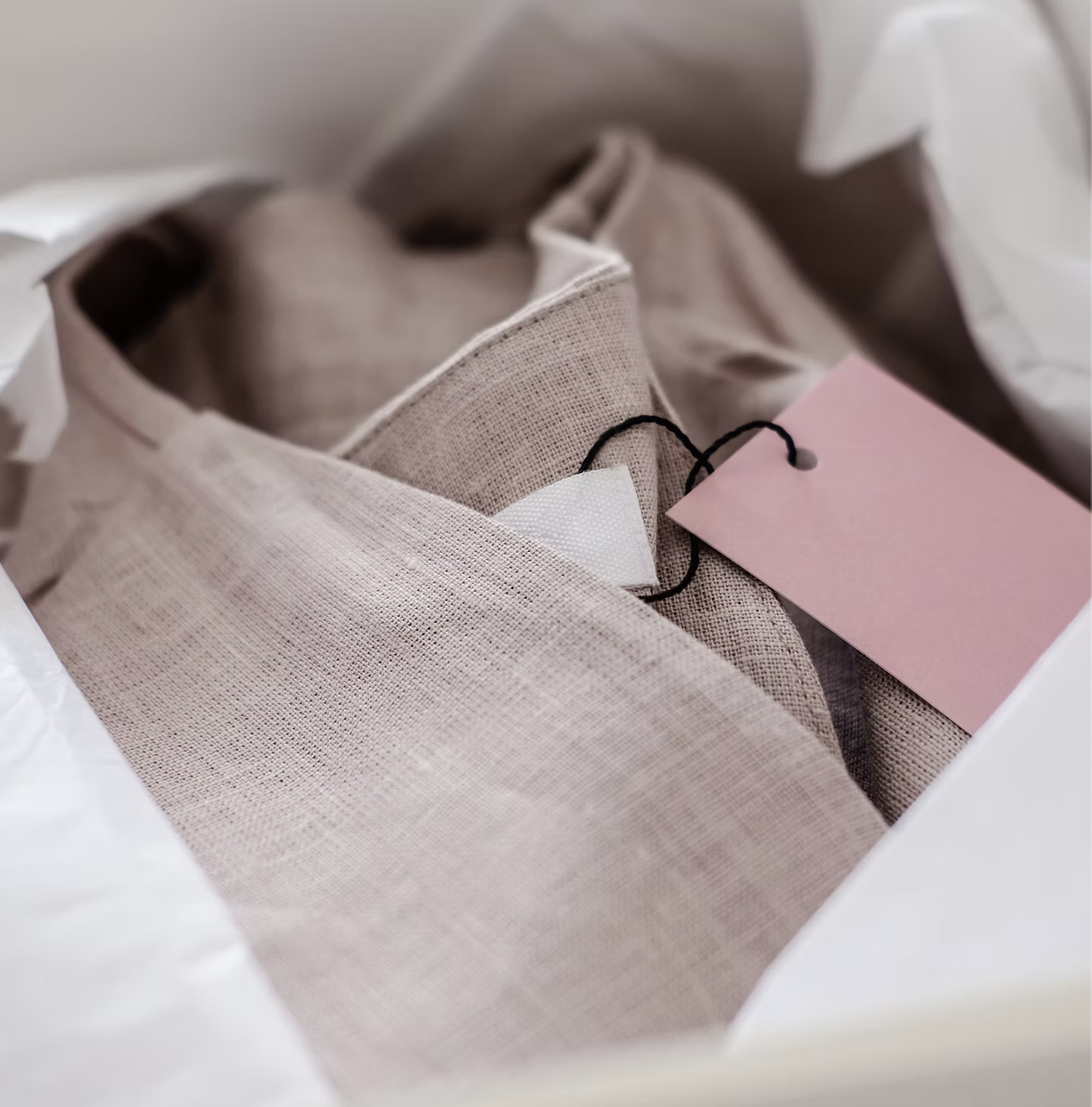 A neatly folded garment with a soft pink brand tag in tissue